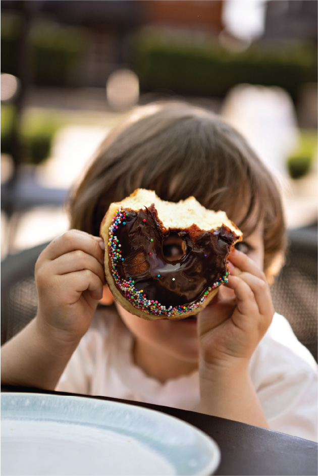 Child holding a donut over their face